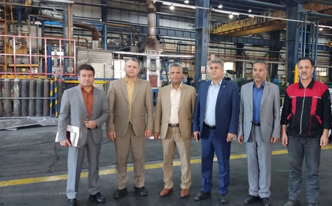 علی اصغر نصیری به‌همراه جمعی از همکاران و مدیران، در سالن تولید کارخانه.